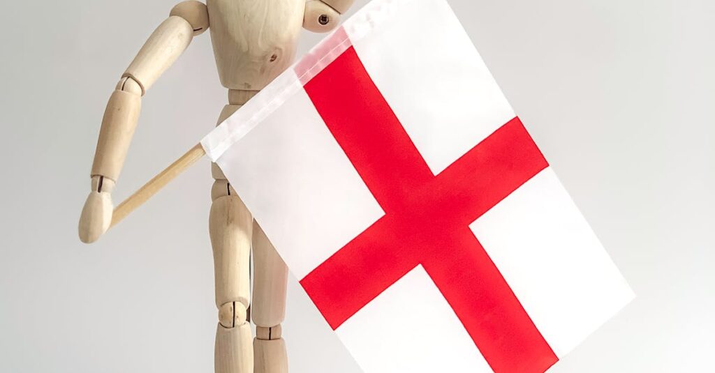 A wooden mannequin celebrates holding an England flag, symbolizing patriotism and support.